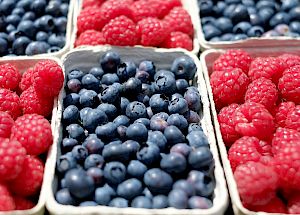 Fresh raspberries and blueberries in boxes, vibrant and ripe, ready to eat.