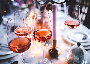 Glasses of rosé wine on a festive table setting with warm lighting.